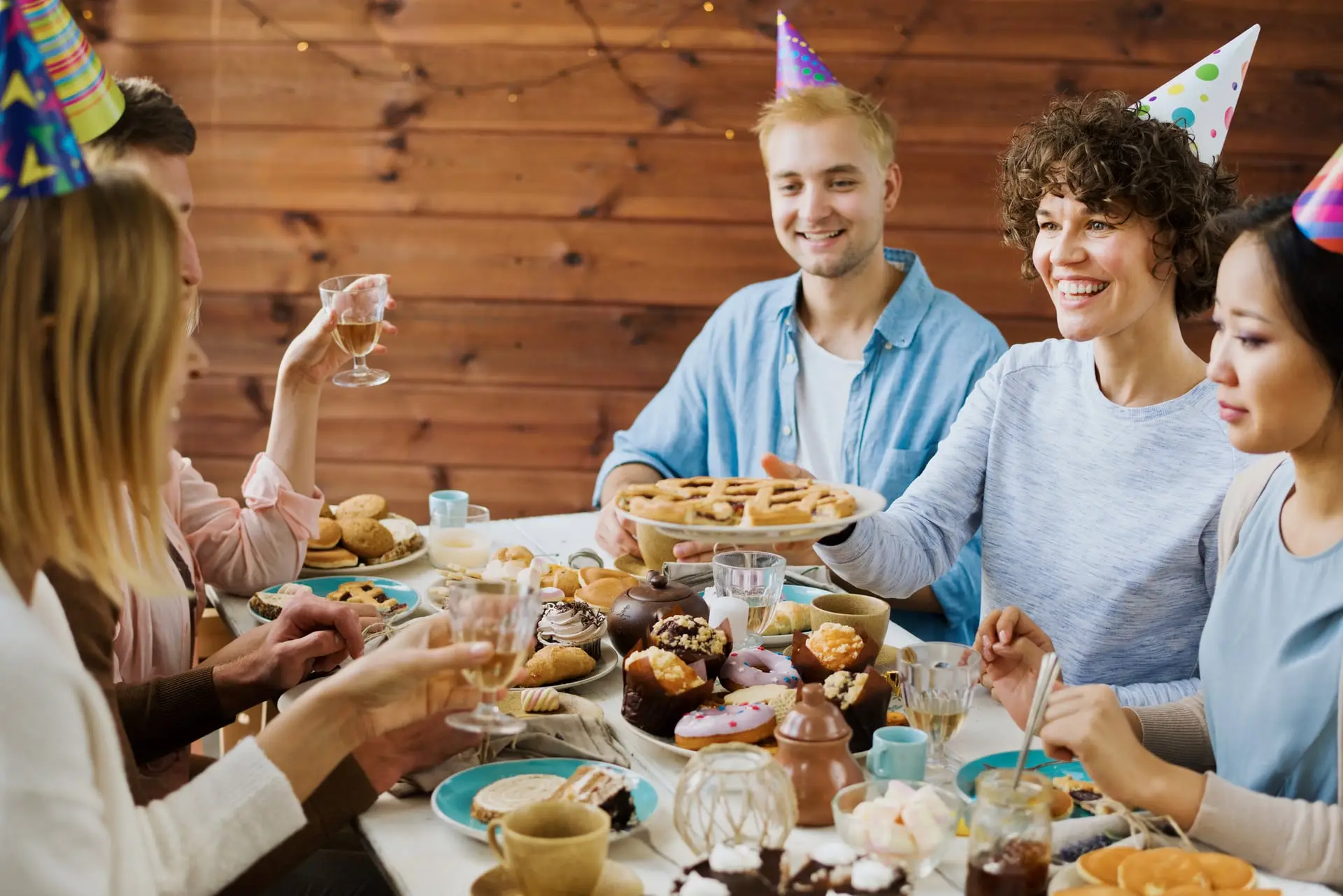 Amis réunis autour d'une table d'anniversaire avec chapeaux de fête