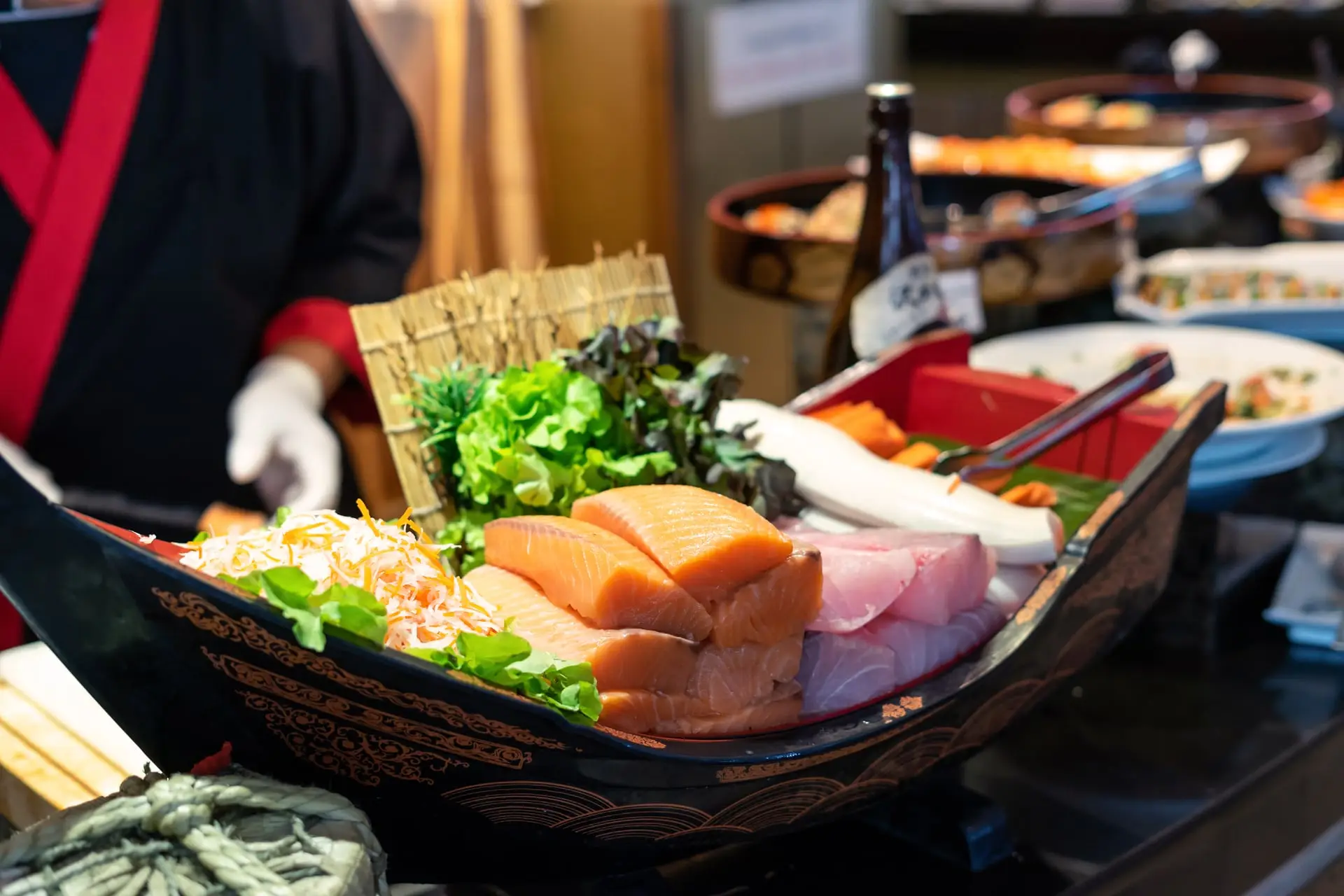 Chef japonais préparant un bateau de sushis et sashimis