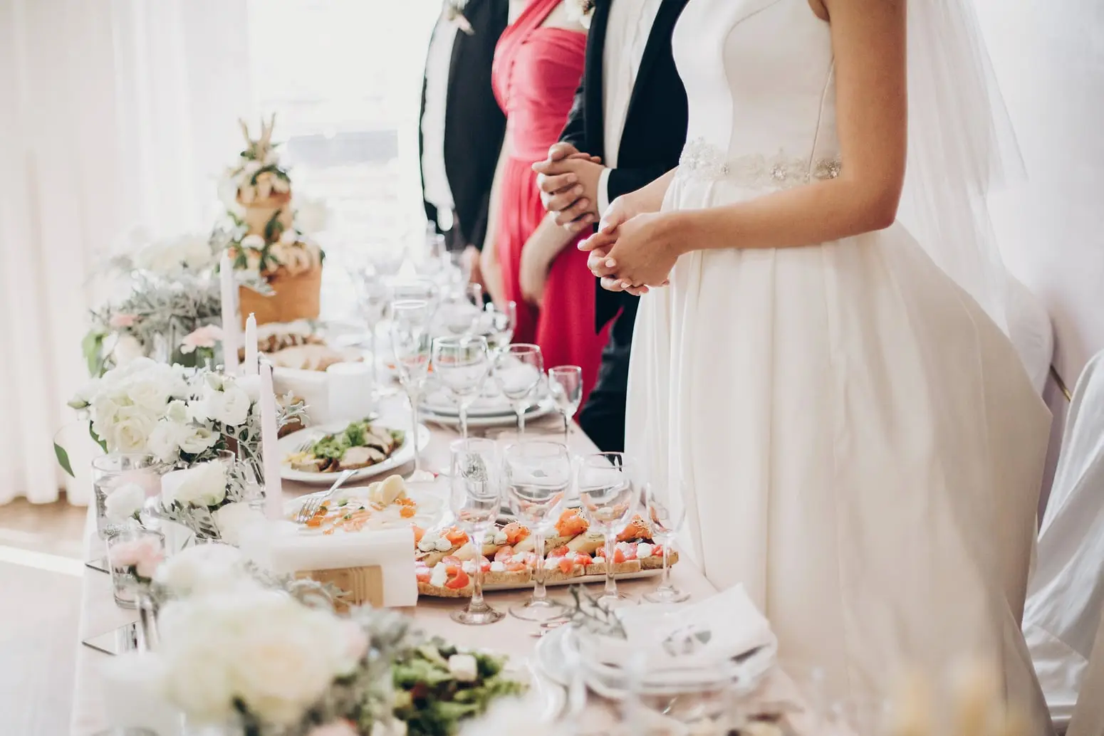 Mariés devant la table de réception dressée de fleurs blanches