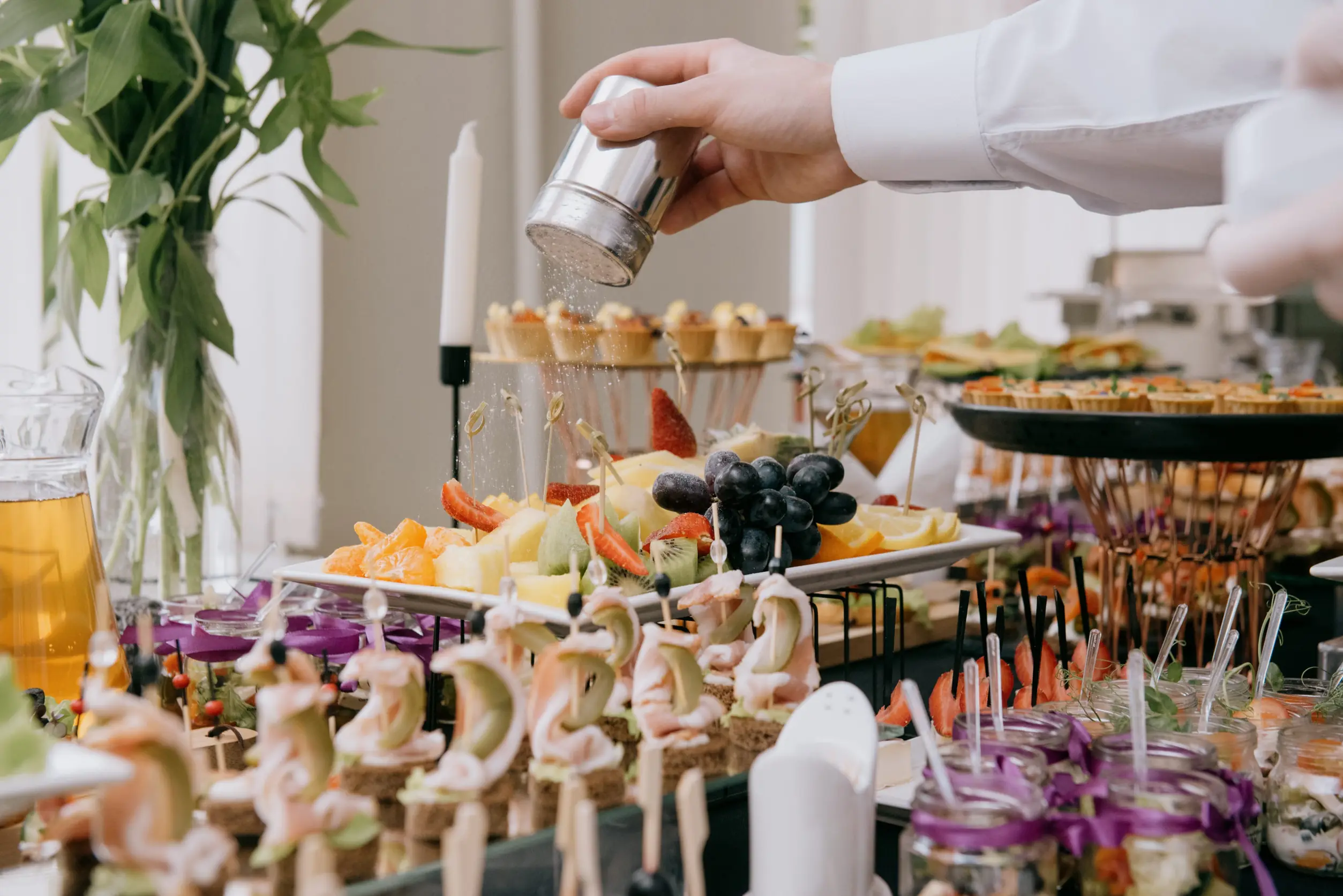 Finition d'un buffet traiteur, fruits et bouchées dressés à la main